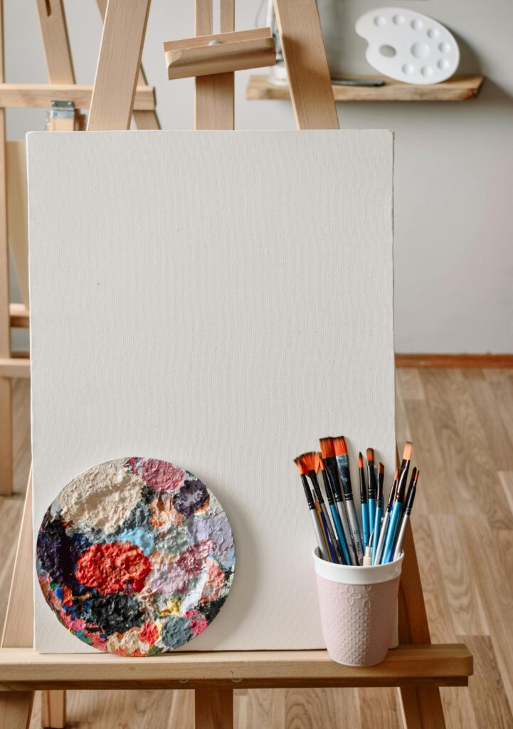 Artistic setup featuring a blank canvas, paint brushes, and palette for creativity.